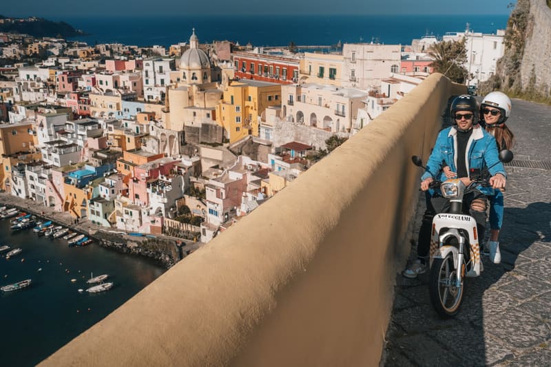 Coppia in scooter elettrico RentEMZ sopra Marina Corricella, Procida